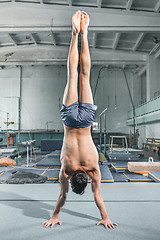 Image showing caucasian man gymnastic acrobatics equilibrium posture at gym background