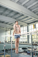 Image showing Male gymnast performing handstand on parallel bars