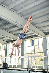 Image showing Male gymnast performing handstand on parallel bars