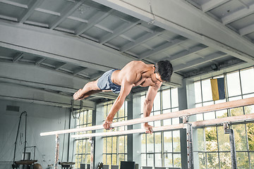 Image showing Male gymnast performing handstand on parallel bars