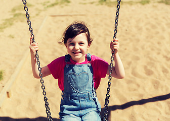 Image showing happy little girl swinging on swing at playground