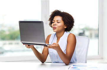 Image showing african woman sending kiss to laptop computer