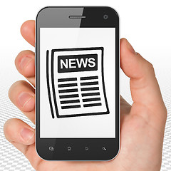 Image showing News concept: Hand Holding Smartphone with Newspaper on display