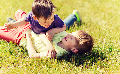 Image showing happy little boys fighting for fun on grass