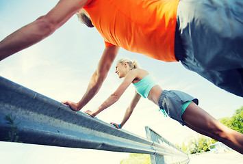 Image showing close up of happy couple doing push-ups outdoors