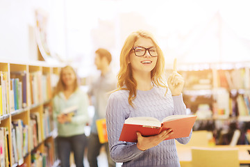 Image showing happy student girl or woman with book in library