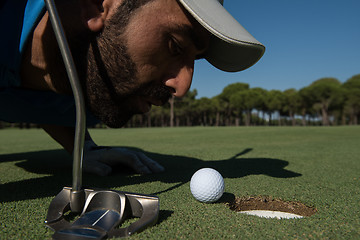 Image showing golf player blowing ball in hole