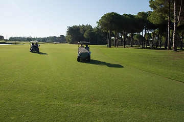 Image showing golf players driving cart at course