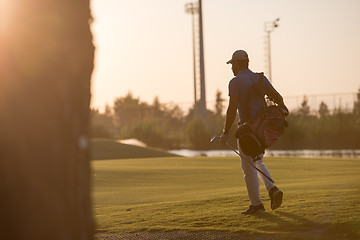 Image showing golfer  walking and carrying golf  bag at beautiful sunset