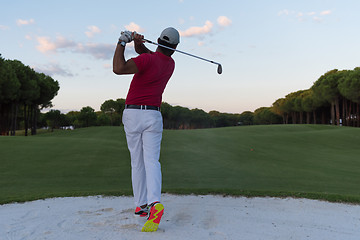 Image showing golfer hitting a sand bunker shot on sunset