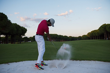 Image showing golfer hitting a sand bunker shot on sunset