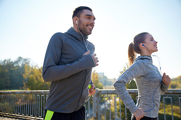 Image showing happy couple with earphones running outdoors