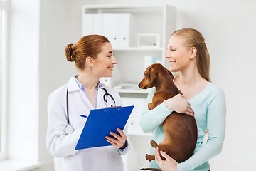 Image showing happy woman with dog and doctor at vet clinic