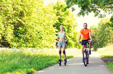 Image showing happy couple with rollerskates and bicycle riding