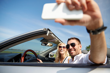 Image showing happy couple in car taking selfie with smartphone