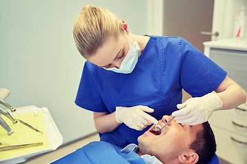 Image showing female dentist checking up male patient teeth