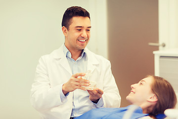 Image showing happy dentist showing jaw layout to patient girl