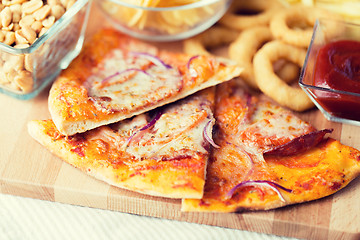 Image showing close up of pizza and other snacks on wooden table