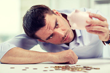 Image showing businessman with piggy bank and coins at office