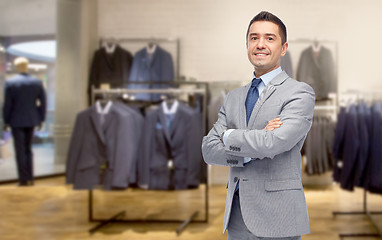 Image showing happy businessman in suit over clothing store