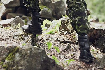 Image showing close up of soldier climbing on rocks in forest