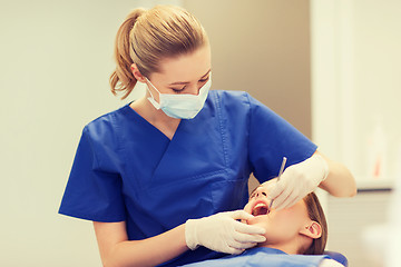 Image showing female dentist checking patient girl teeth