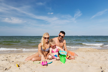 Image showing happy family playing with sand toys on beach