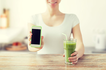 Image showing close up of woman with smartphone and green juice