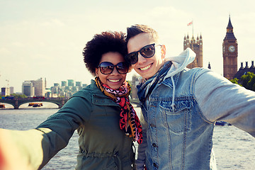 Image showing happy teenage couple taking selfie in london city