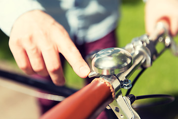 Image showing close up of male hand ringing bell on bike wheel