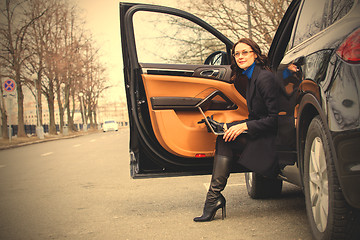 Image showing woman with a laptop sitting on the threshold of the vehicle