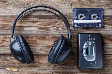 Image showing Headphones, player and retro compact cassette over wooden background. Top view