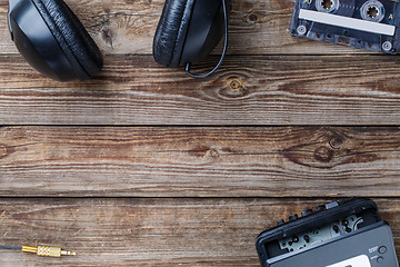 Image showing Cassette tapes, cassette player and headphones over wooden table. top view.