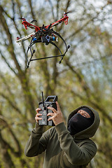 Image showing Man in mask operating a drone with remote control.