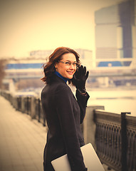 Image showing friendly brunette with a computer outdoors