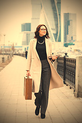 Image showing woman in a light overcoat with a wooden case and a notebook