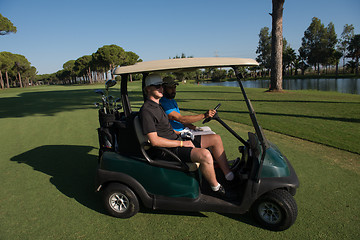 Image showing golf players driving cart at course