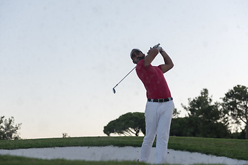 Image showing golfer hitting a sand bunker shot on sunset