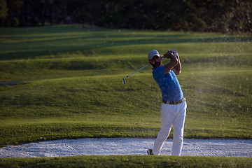 Image showing golfer hitting a sand bunker shot on sunset