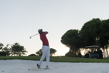 Image showing golfer hitting a sand bunker shot on sunset