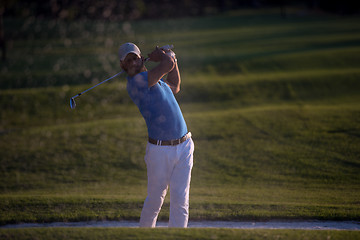 Image showing golfer hitting a sand bunker shot on sunset