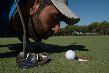 Image showing golf player blowing ball in hole