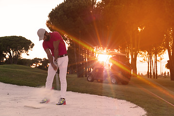 Image showing golfer hitting a sand bunker shot on sunset