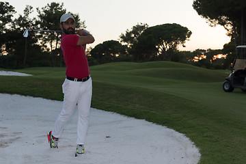 Image showing golfer hitting a sand bunker shot on sunset