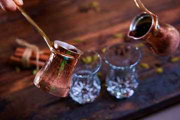 Image showing To pour arabic coffee in cups on wooden background.