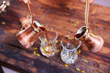 Image showing To pour arabic coffee in cups on wooden background.