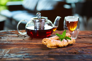 Image showing Tasty eclair and cup of tea on wooden table