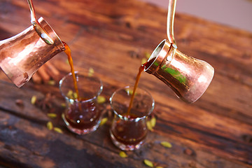 Image showing To pour arabic coffee in cups on wooden background.