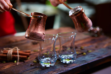 Image showing To pour arabic coffee in cups on wooden background.