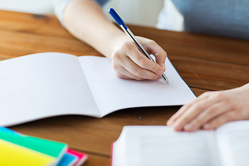 Image showing close up of student with book and notebook at home